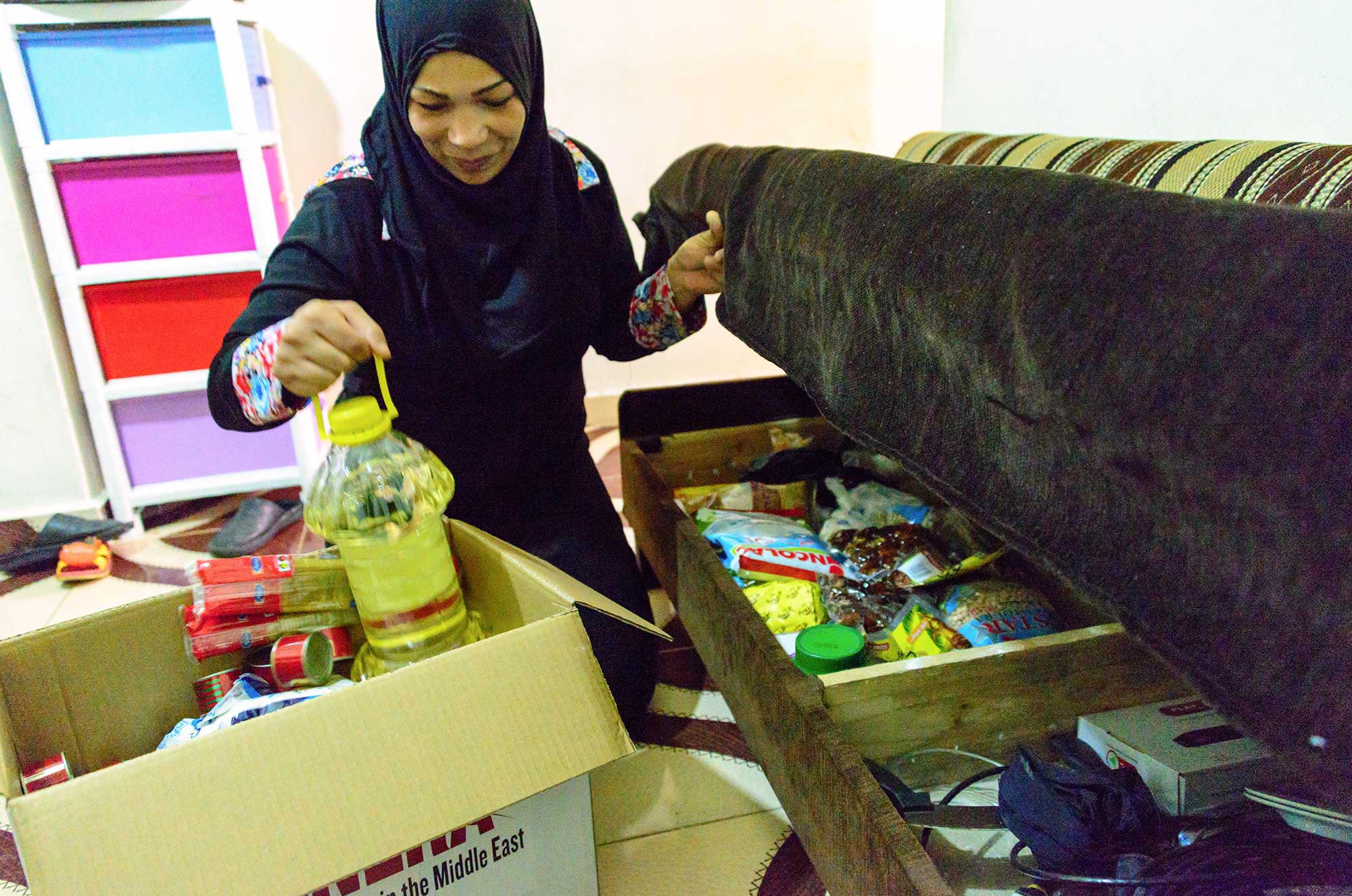 Samira stows away the items she received in her donated Ramadan food parcel.