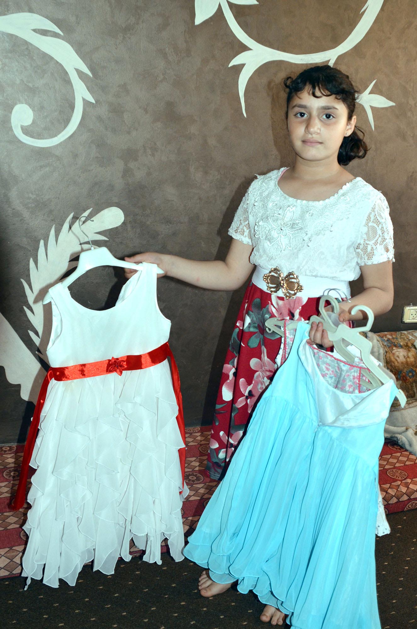Malak holds up her dresses from Syria.