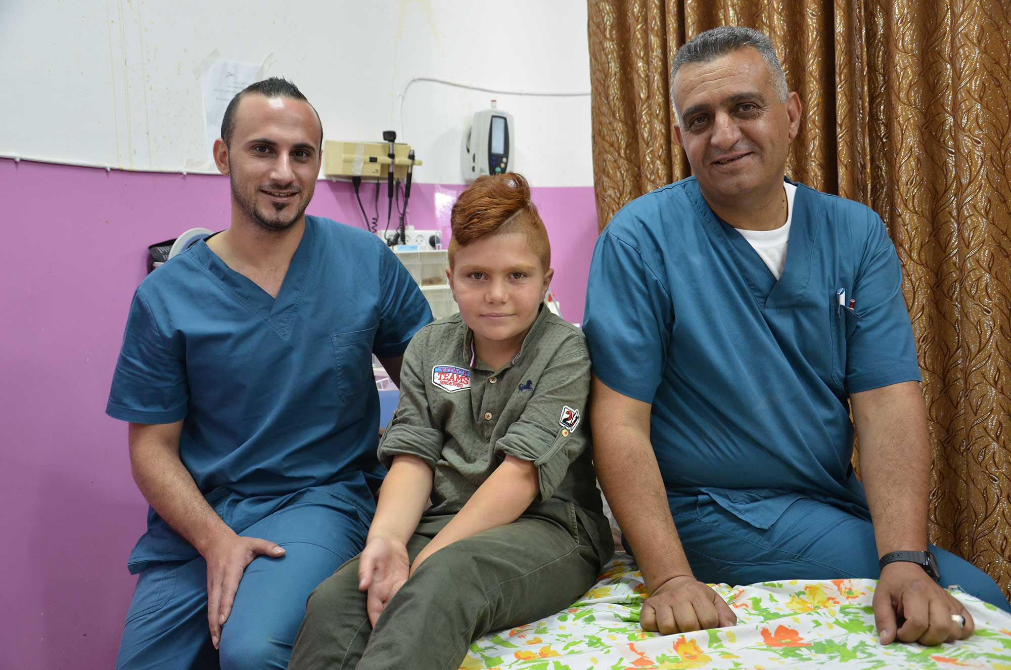 Dr. Salem Dudeen and Dr. Ali Ghrayeb pose for a picture with young Abdallah.