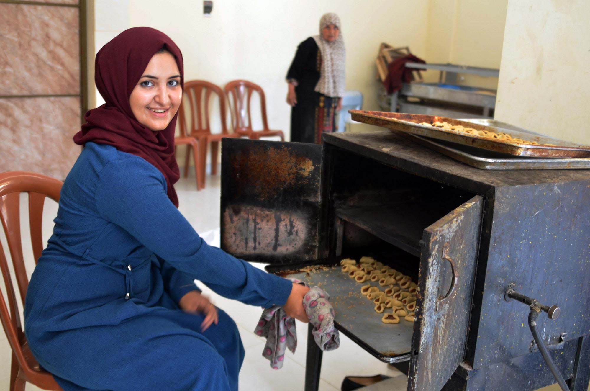 Aya takes date cookies out of the co-op oven.