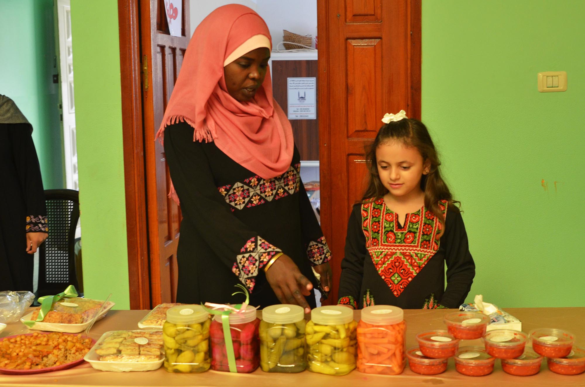 Aziza shows a young girl how to pickle vegetables.