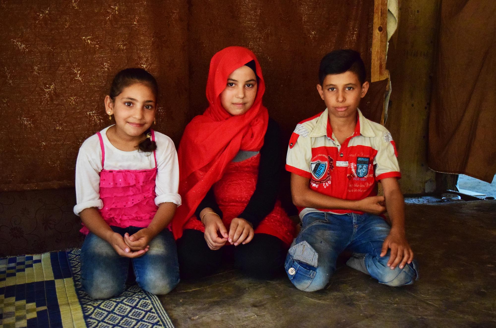 Dalaa, Shahed and Kayed sit in their tent at in informal tented settlement in Bourj Al Arab, Lebanon.
