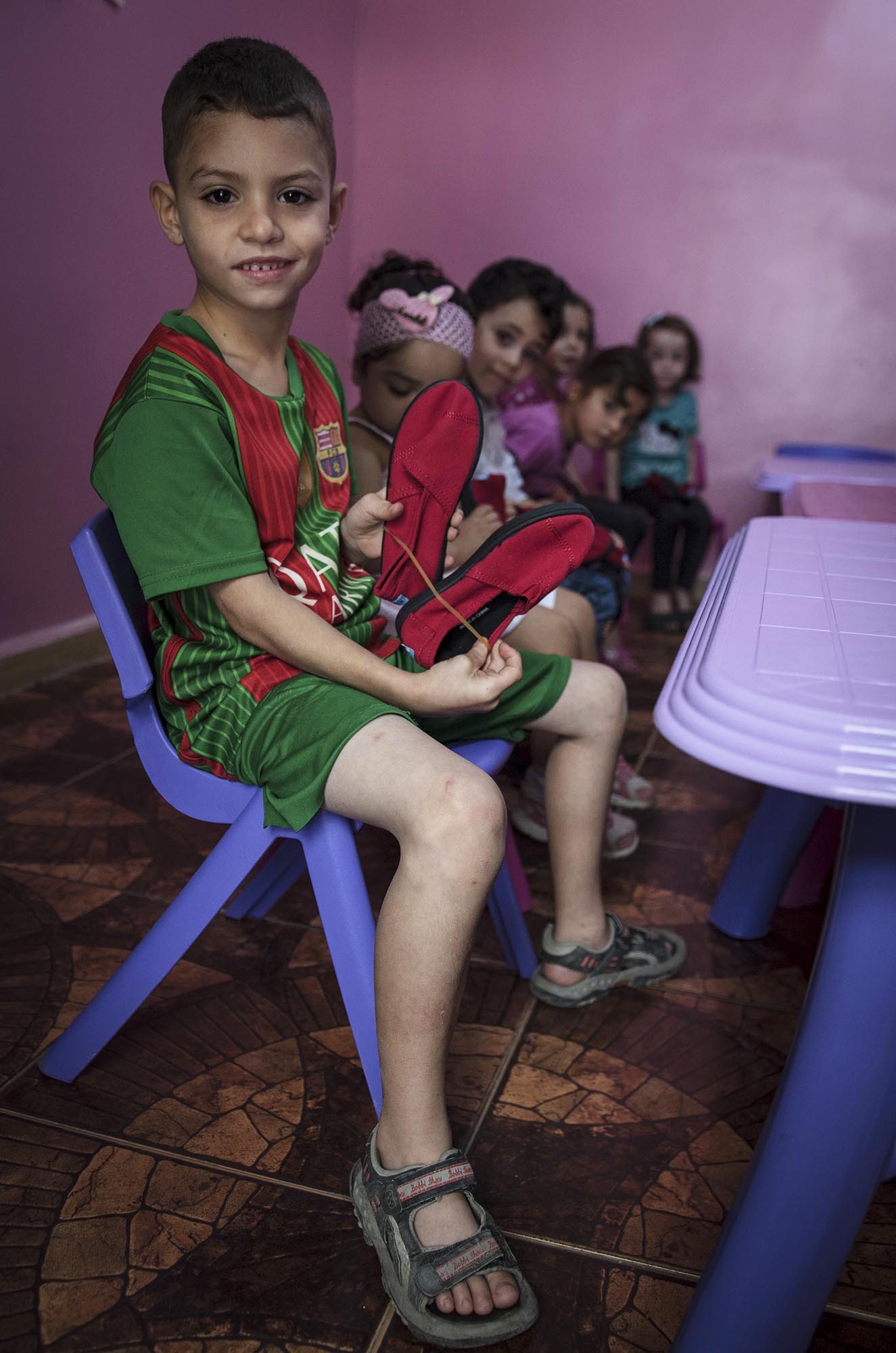 Preschoolers in Beddawi Camp in Lebanon picks up brand new TOMS shoes.