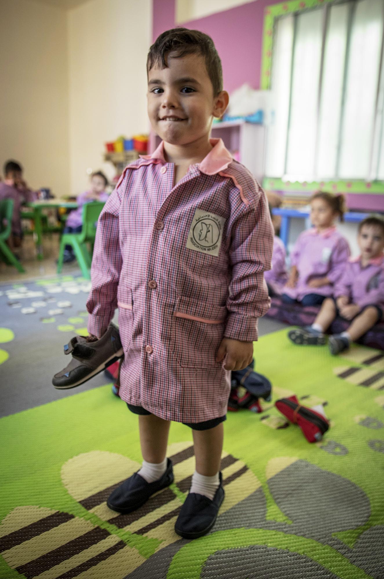 A preschooler in Beddawi Camp in Lebanon picks up brand new TOMS shoes.