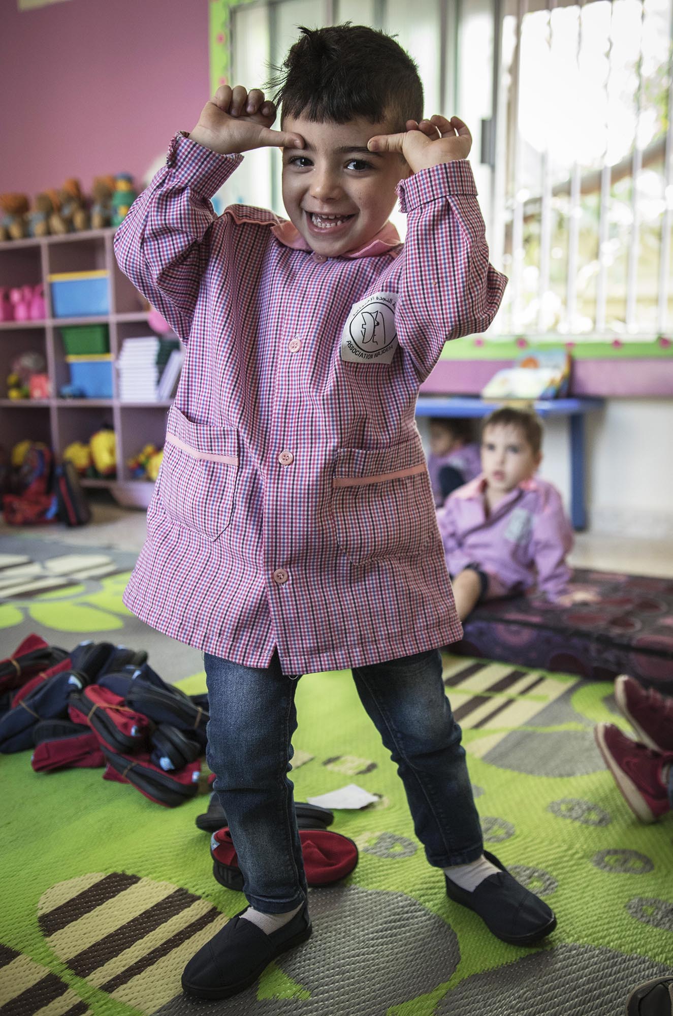 A preschooler in Beddawi Camp in Lebanon picks up brand new TOMS shoes.