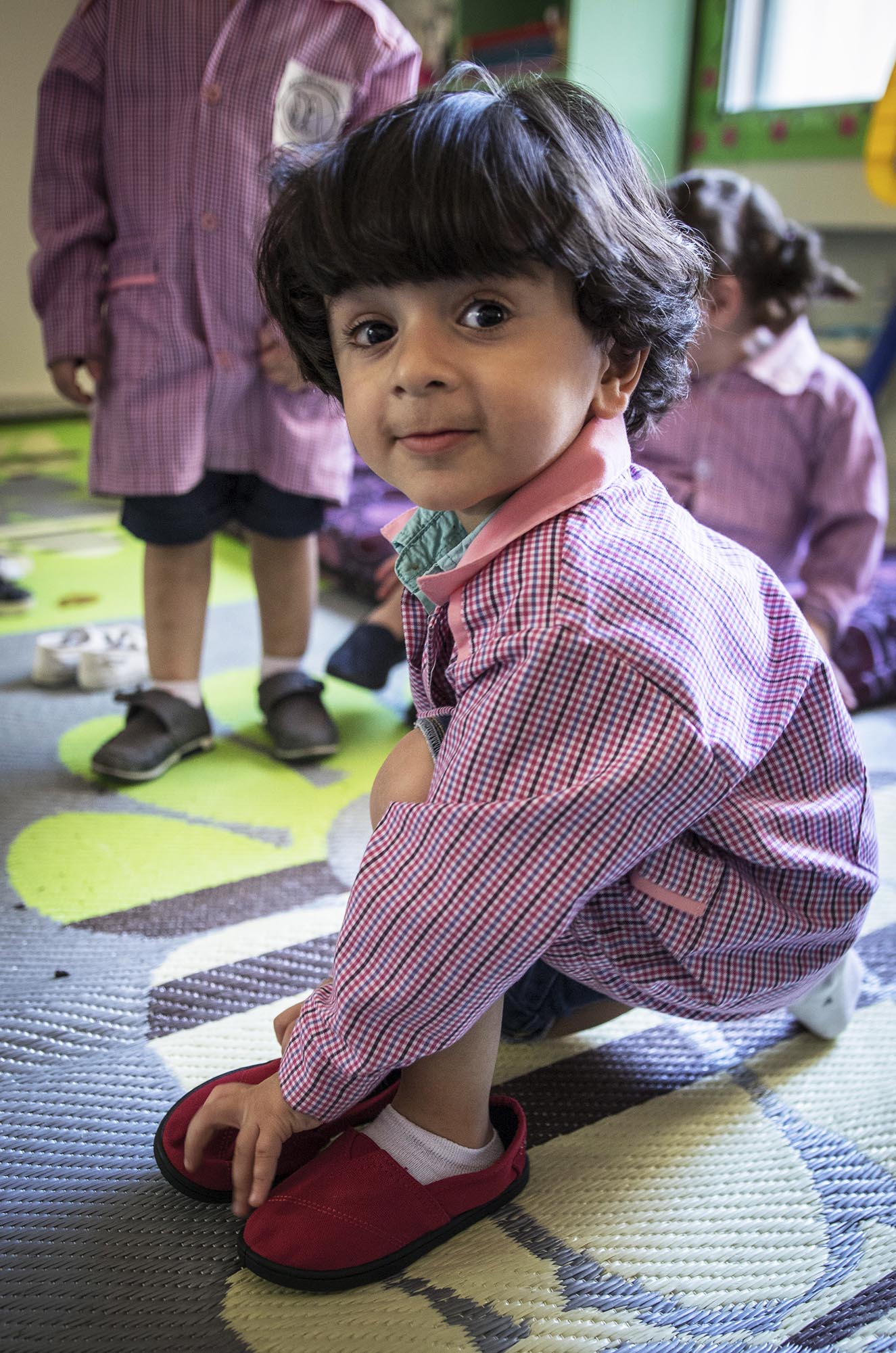 A preschooler in Beddawi Camp in Lebanon picks up brand new TOMS shoes.