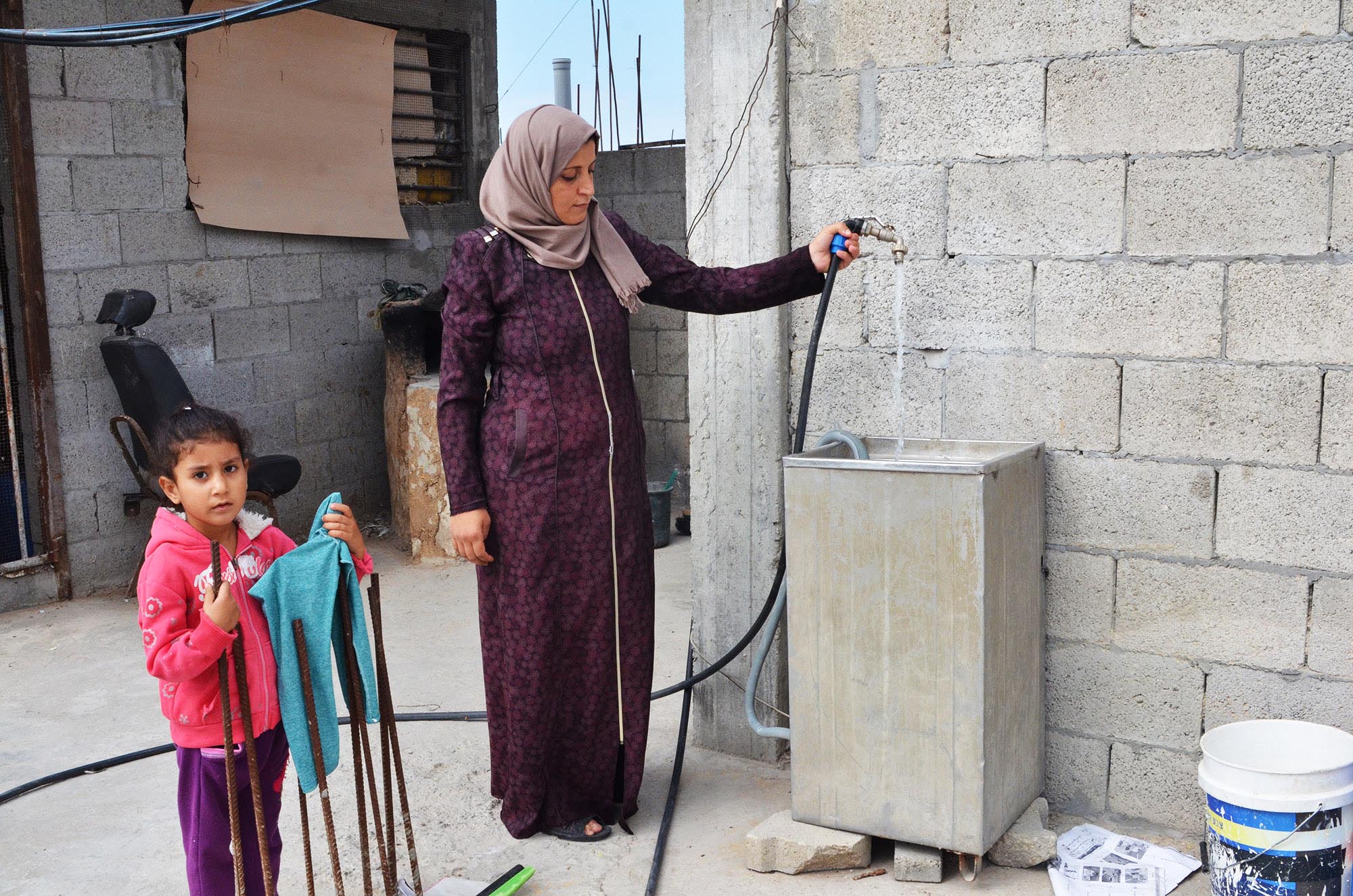 Nadia and her daughter use water from the rebuilt well.