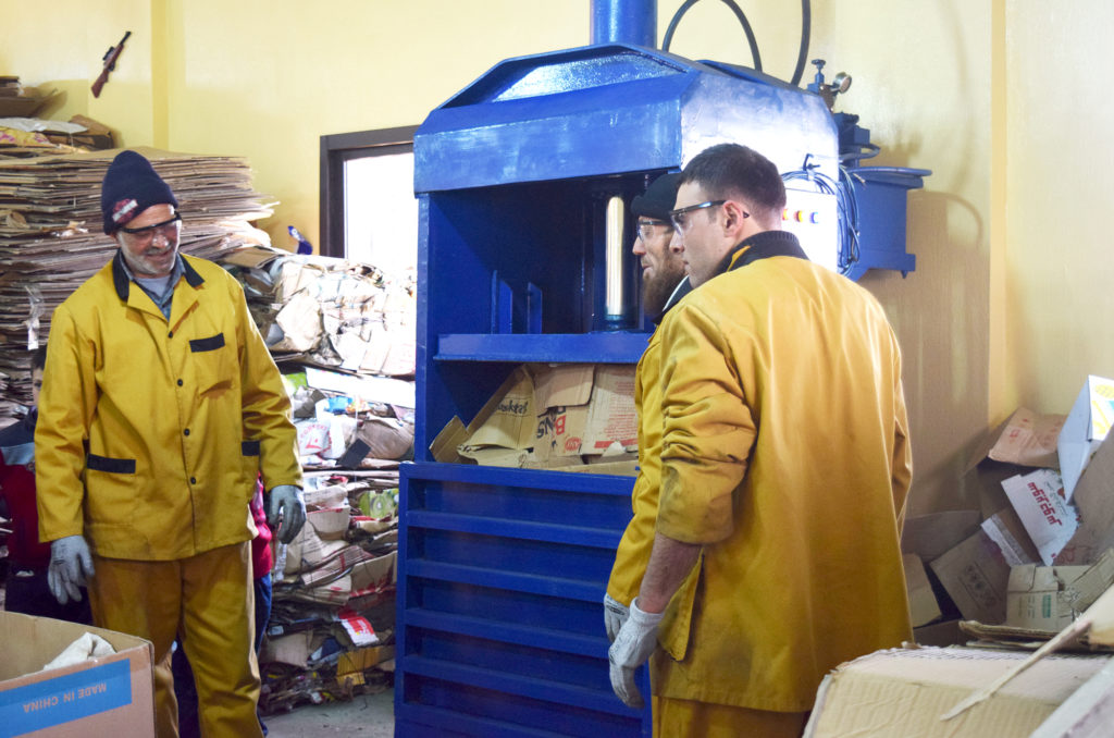 Workers use a compactor at the Mashha sorting facility