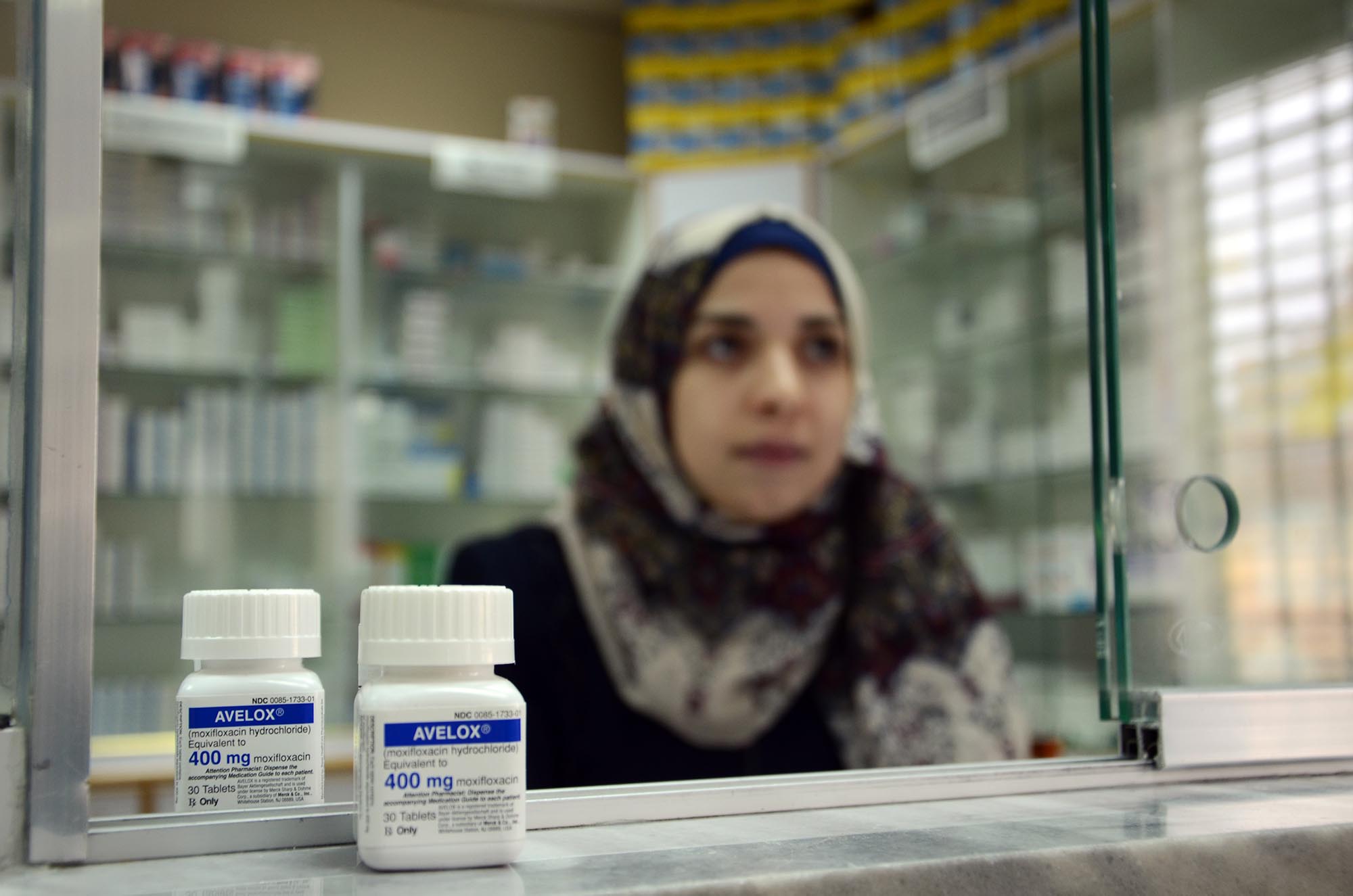 A pharmacist at Hebron's charitable medical center along with medicine delivered by Anera.