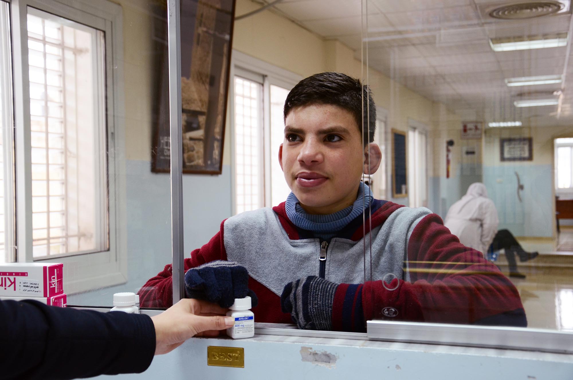A Palestinian teen picks up medications for his grandmother at the Hebron charitable medical center.