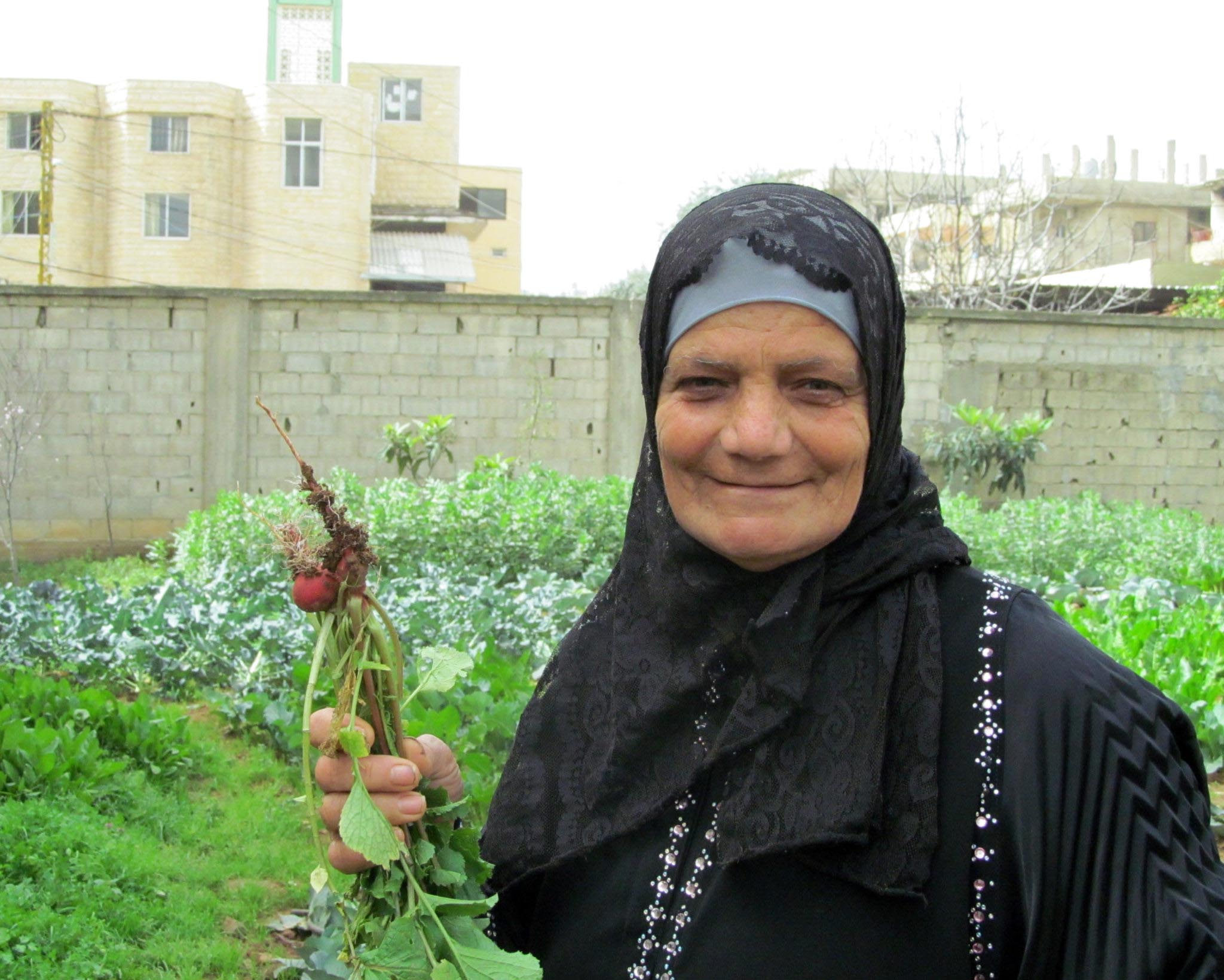 Sobheya holds up her radishes that she carefully cultivated in the garden Anera installed in her Nahr El Bared community.
