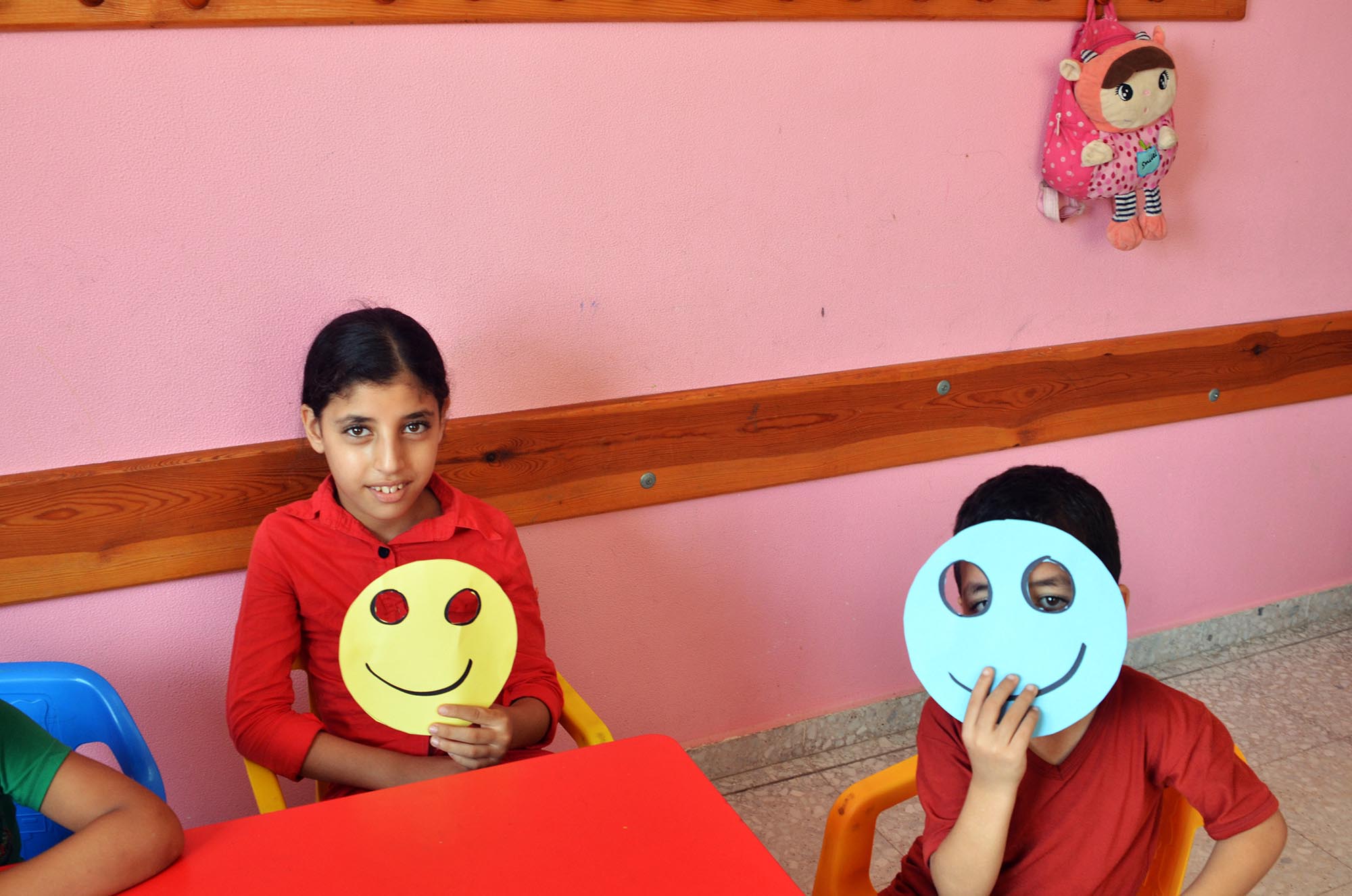 Kids are engaged in cut and paste activities to make masks featuring different 'emotions'.