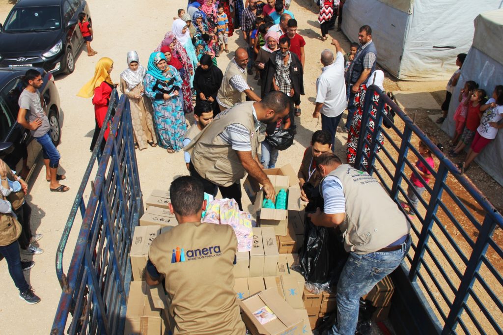 Anera staff and volunteers distribute hygiene kits to camp residents