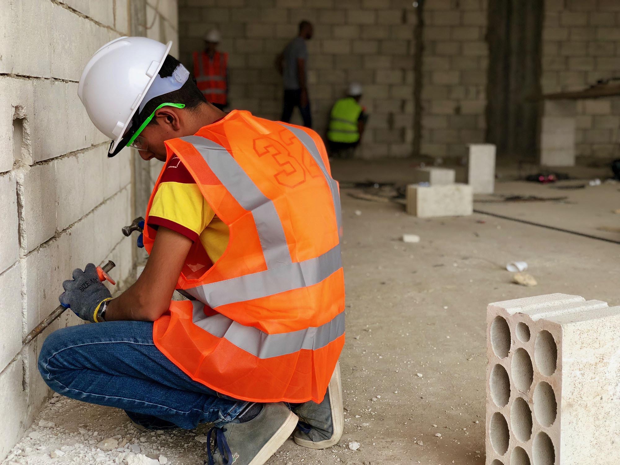 After completing Anera’s Home Electricity course in the Bekaa Valley, Tarek, 16 years old from Syria, carving a concrete wall, to install an electrical socket at a construction site.