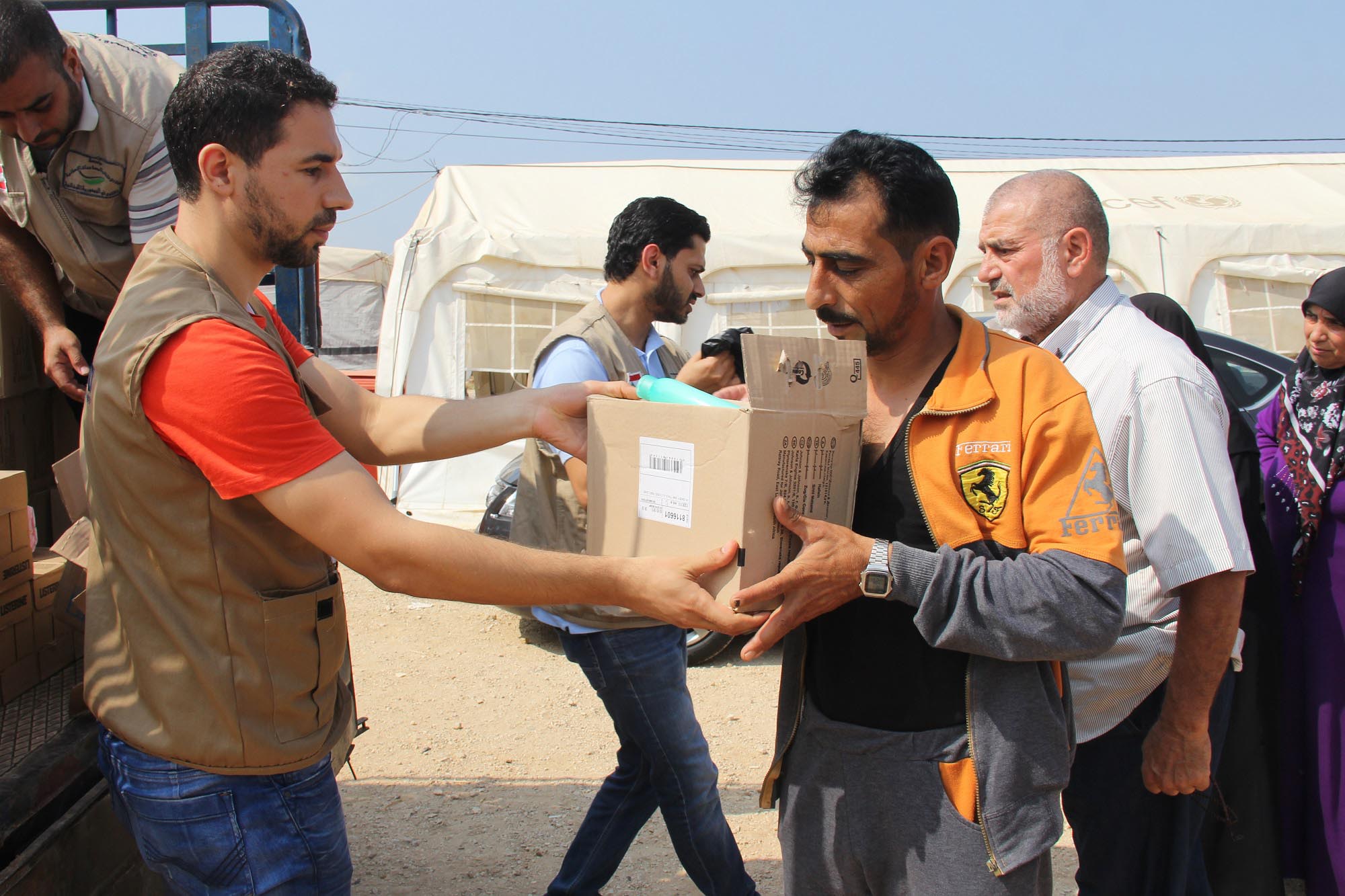 A camp resident receives a Johnson & Johnson hygiene kit from an Anera staff member