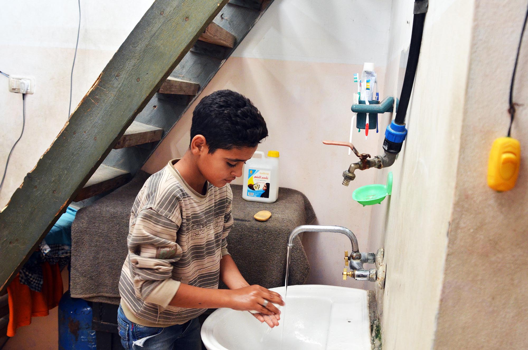 Ahlam's son uses the newly connected tap.