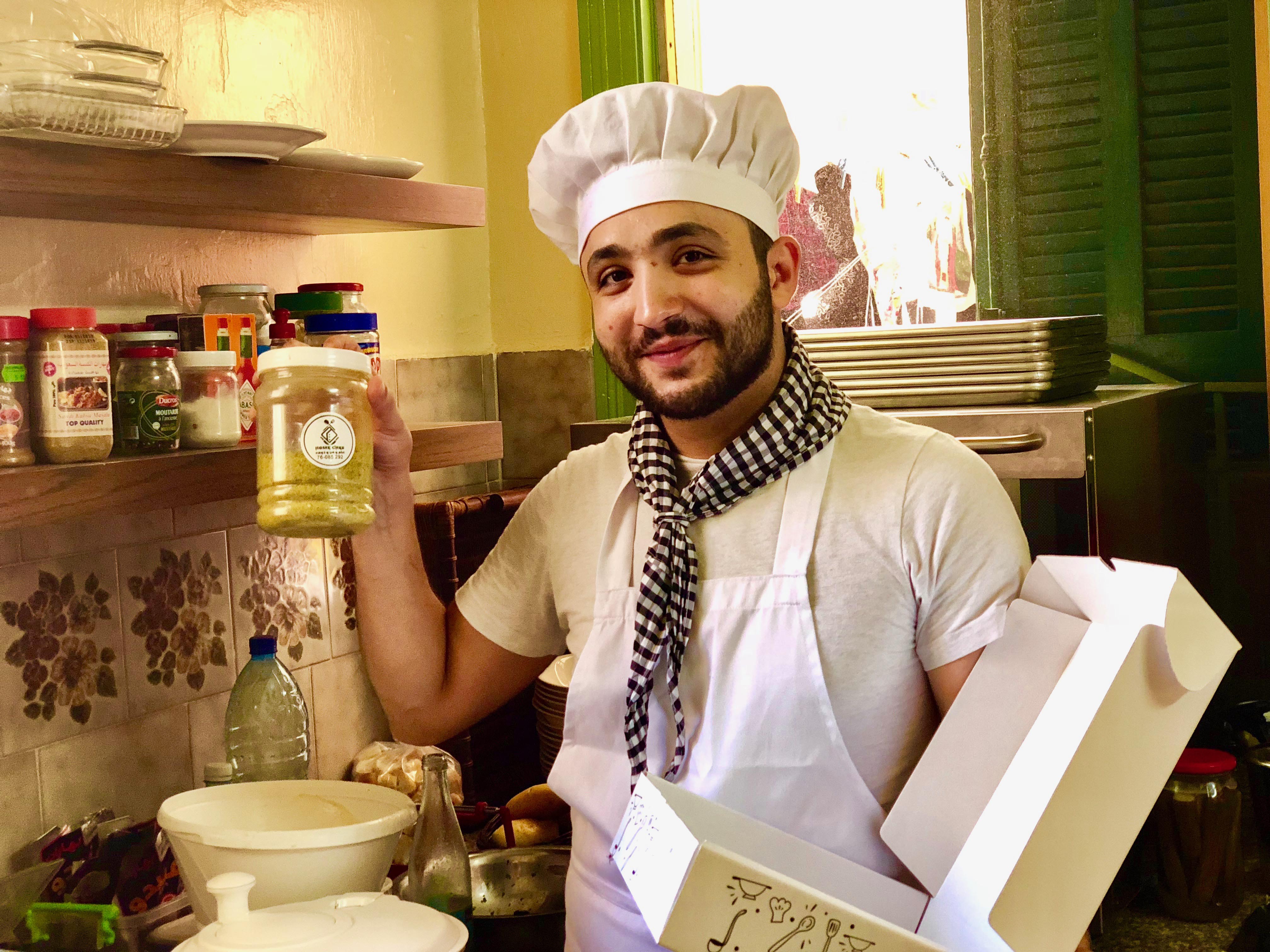 Chef Ahmad smiling, showing us his homemade spices blend and varying his personally designed food packaging box.