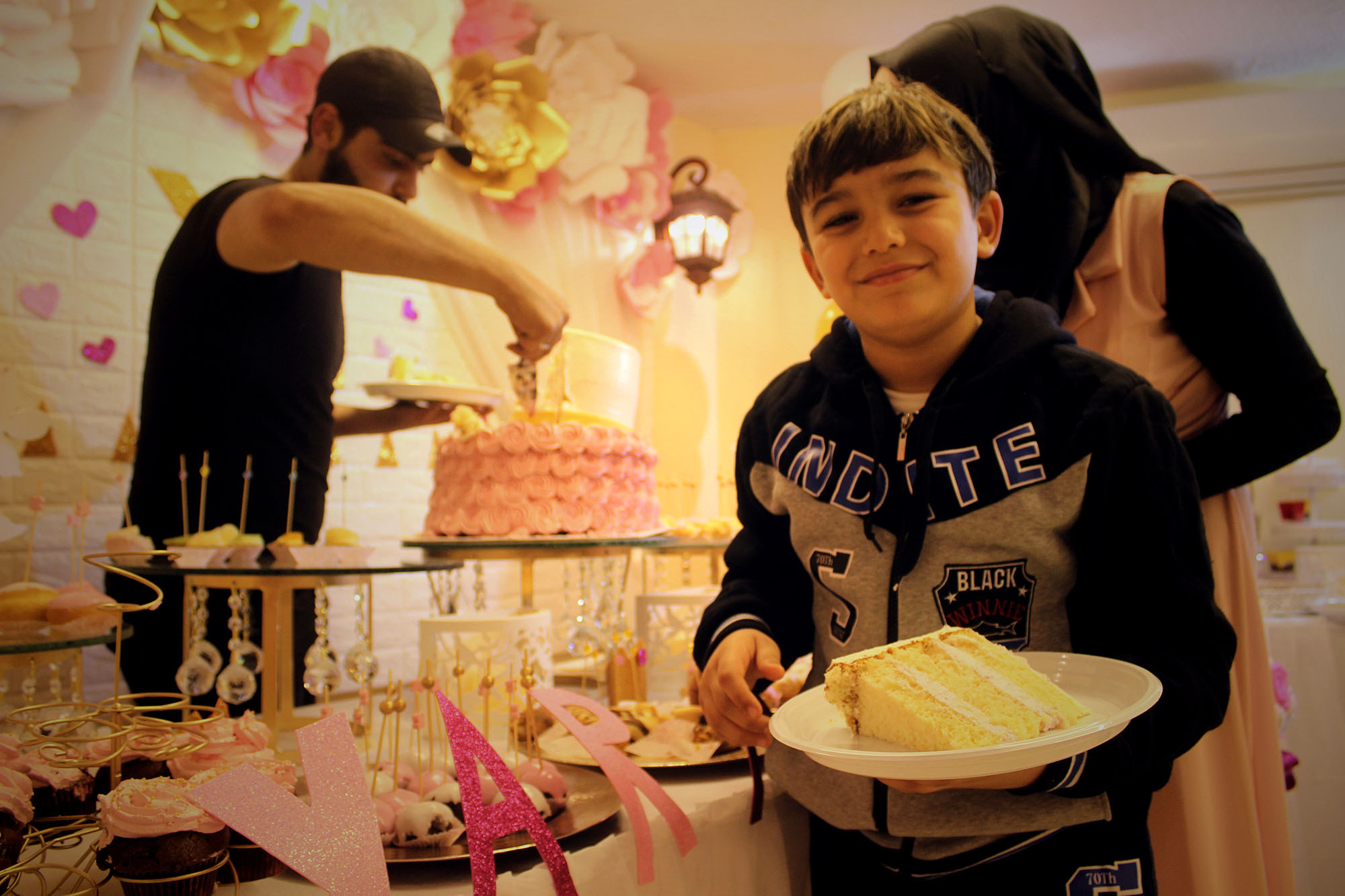A boy shows off a cake made by the event planning team.