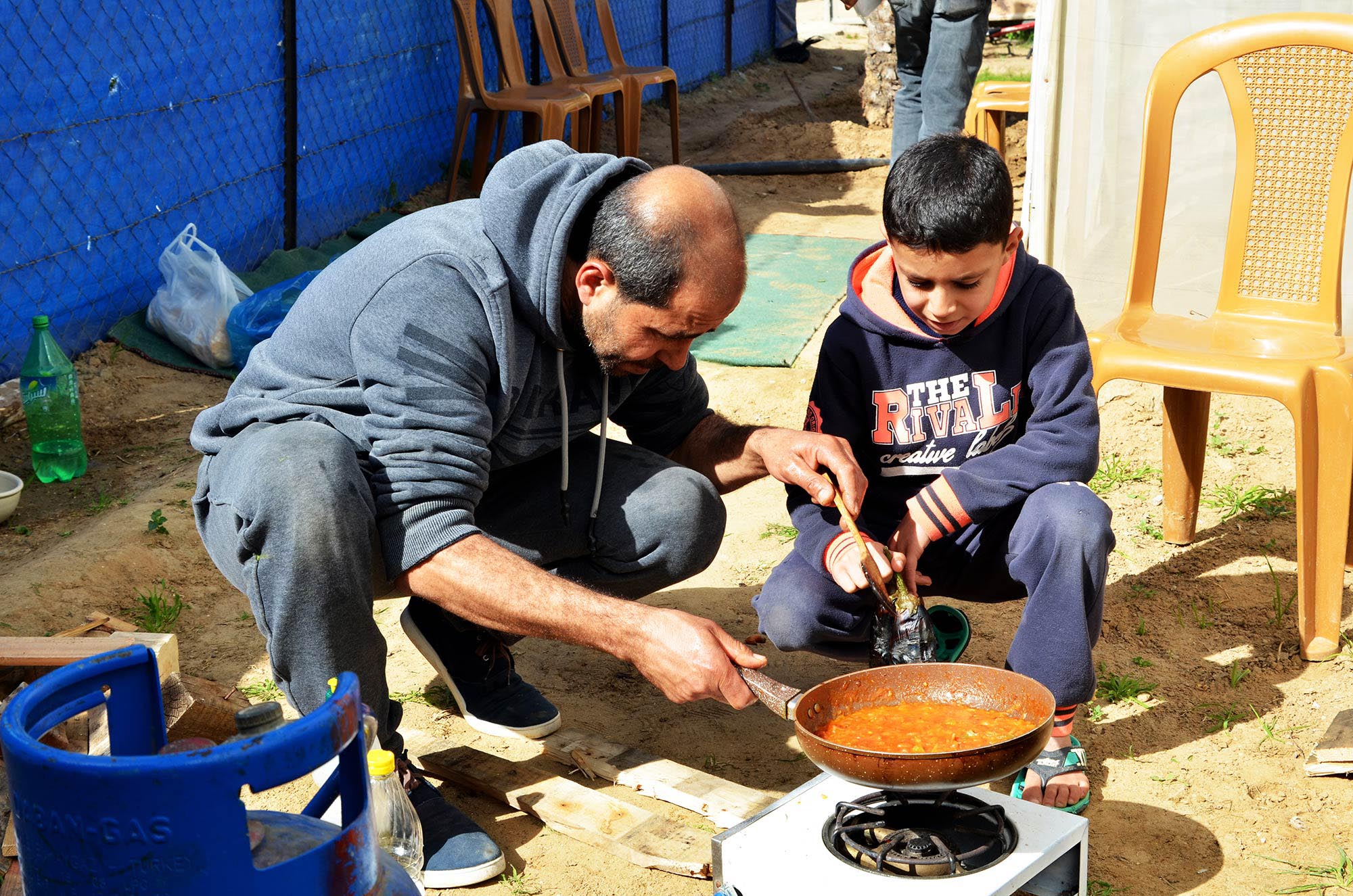 Mohamed and Moetasem cook shakshouka together using fresh tomatoes from their Anera-built greenhouse.