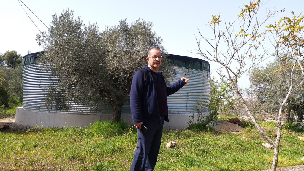 Naser Qadous, Anera's Agricultural Programs Manager, explains how the water reservoir behind him will be used for the irrigation of public parks and orchards.
