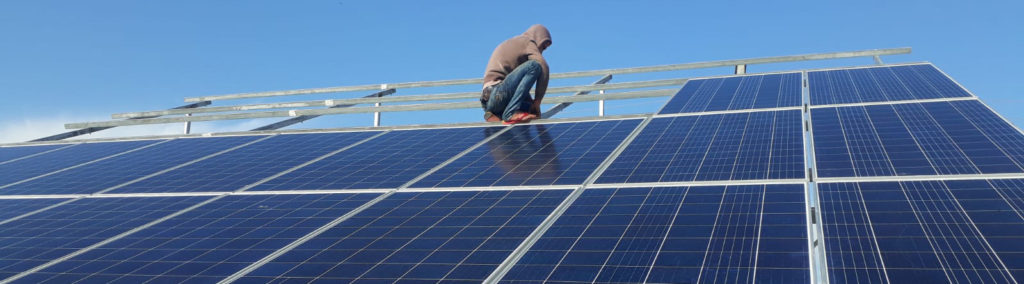 A construction worker installs Anera provided solar panels on top of the Wounded Child Clinic in Wadi Al-Salqa, Gaza.