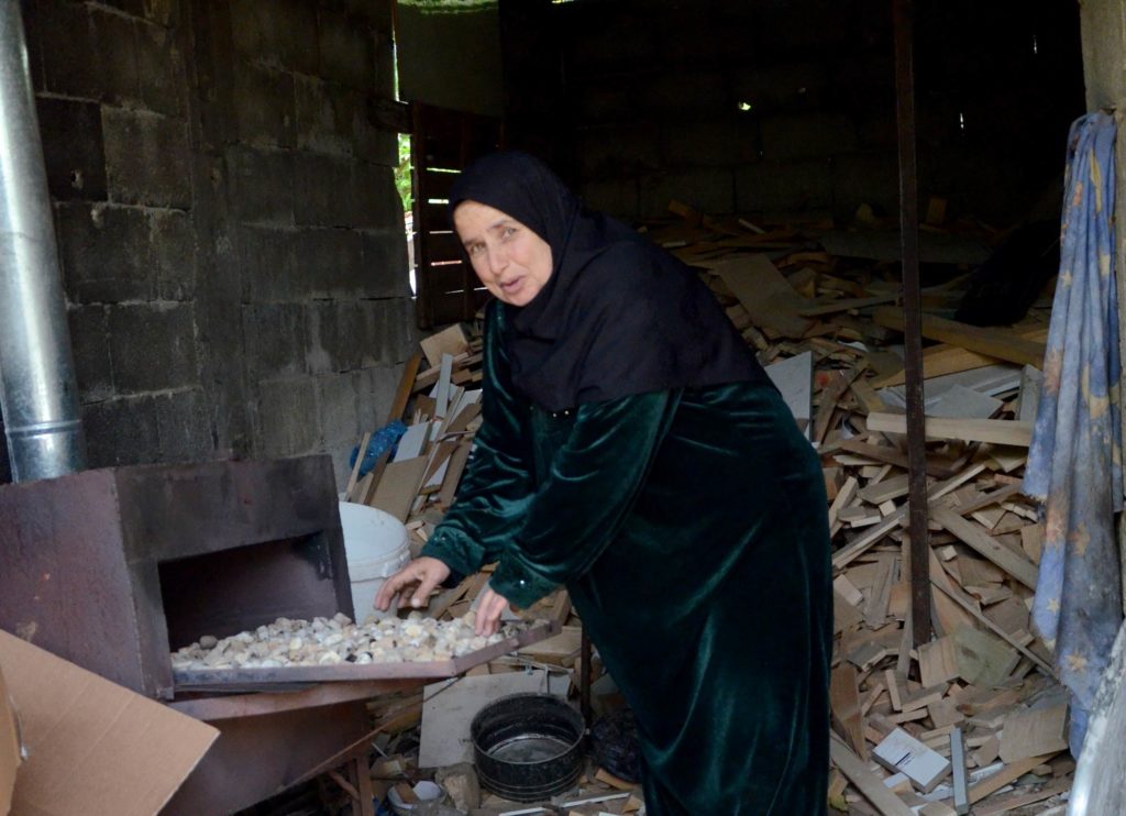 Khyria puts coal in her oven to heat it in preparation for making her famous bread.