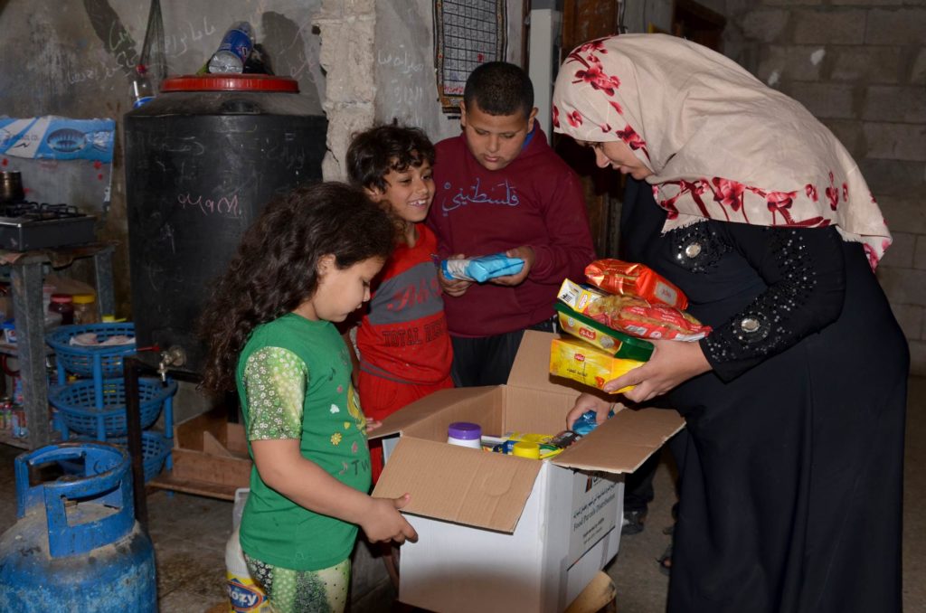 Mona and her children open a food parcel in their home.