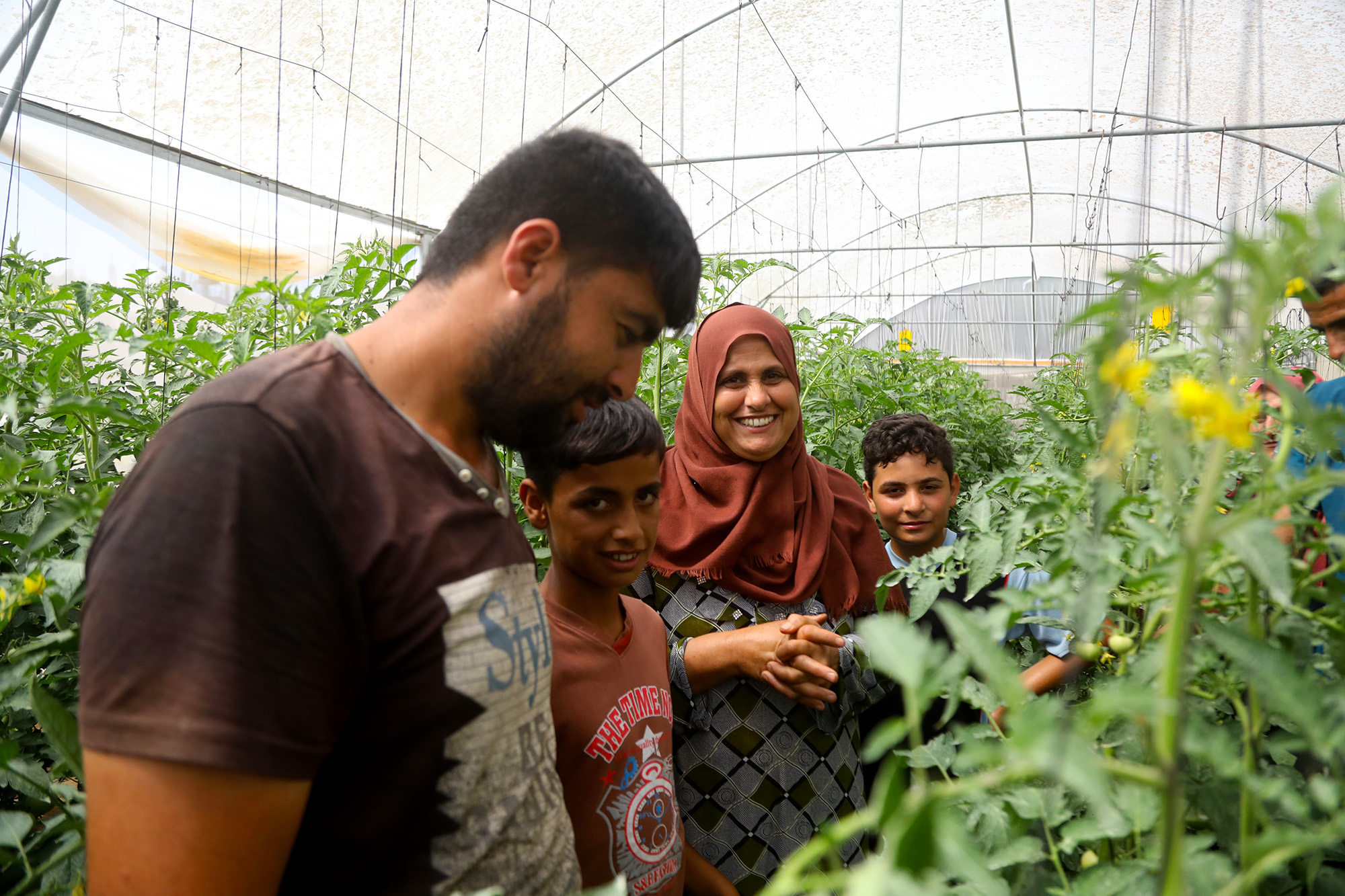 Fayrooz gives the camera a smile while showing off some of her produce in her Anera-built greenhouse.