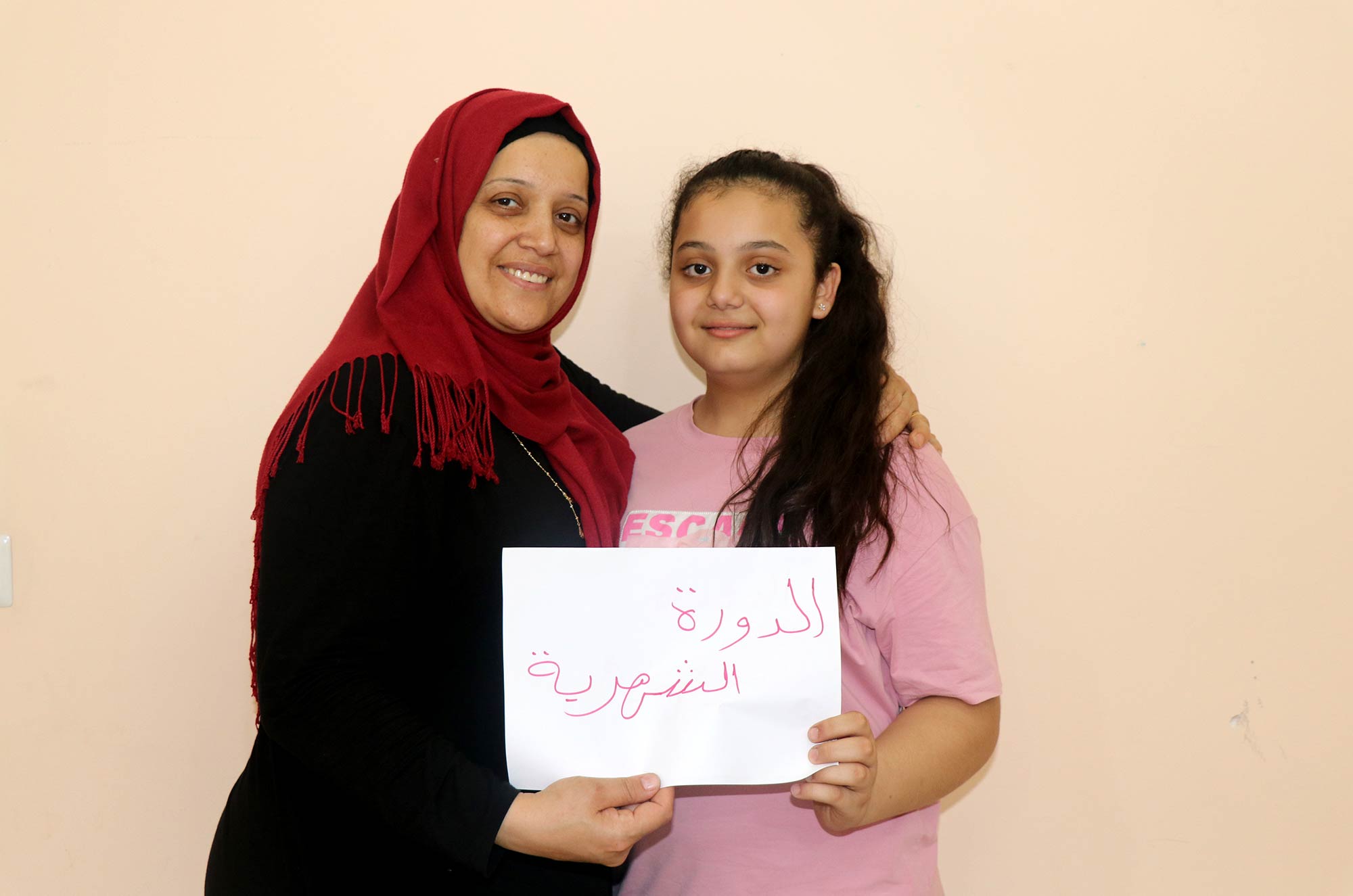 Souad and daughter Najah hold a sign on menstruation