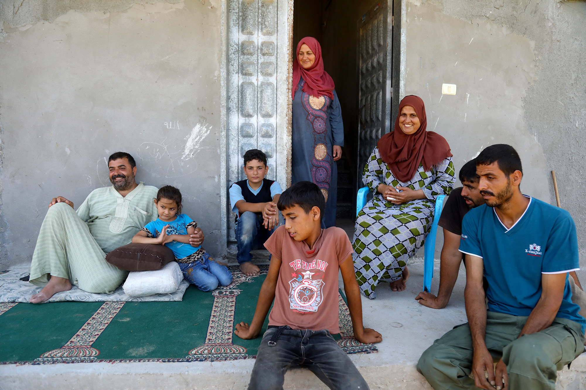 The Al Adham family, who benefit from an Anera greenhouse, sit in front of their family home in Beit Lahia, Gaza.