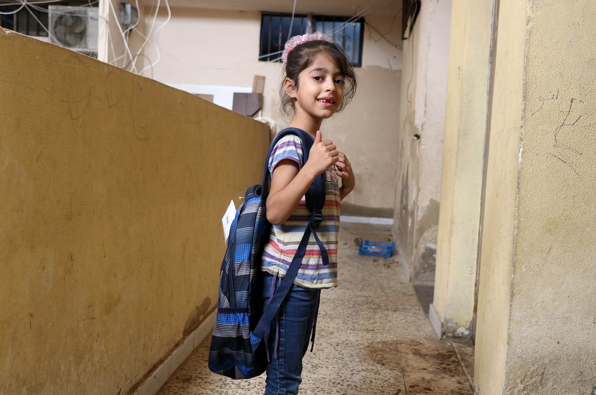 A young student shows off her new school bag at Burj El Barajneh refugee camp, Beirut, Lebanon.