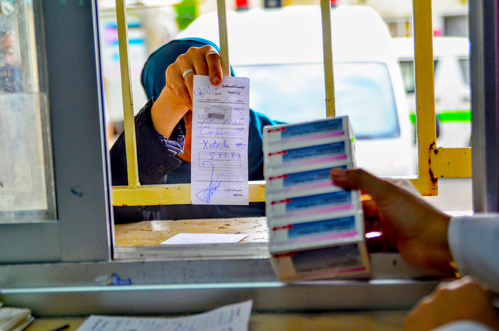 A patient shows a pharmacist her prescription for capecitabine. Gaza cancer patients now have access to a full course of medicine at the Al Shifa Hospital pharmacy.