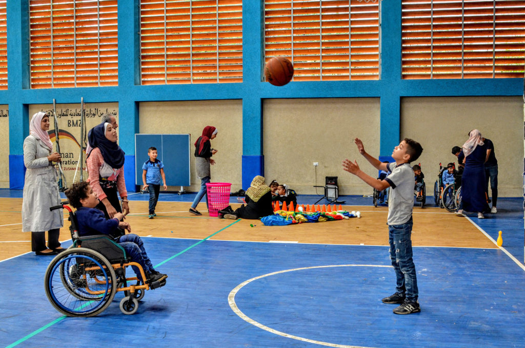Abed passes a basketball to another child while Dalia watches on the court in Gaza.