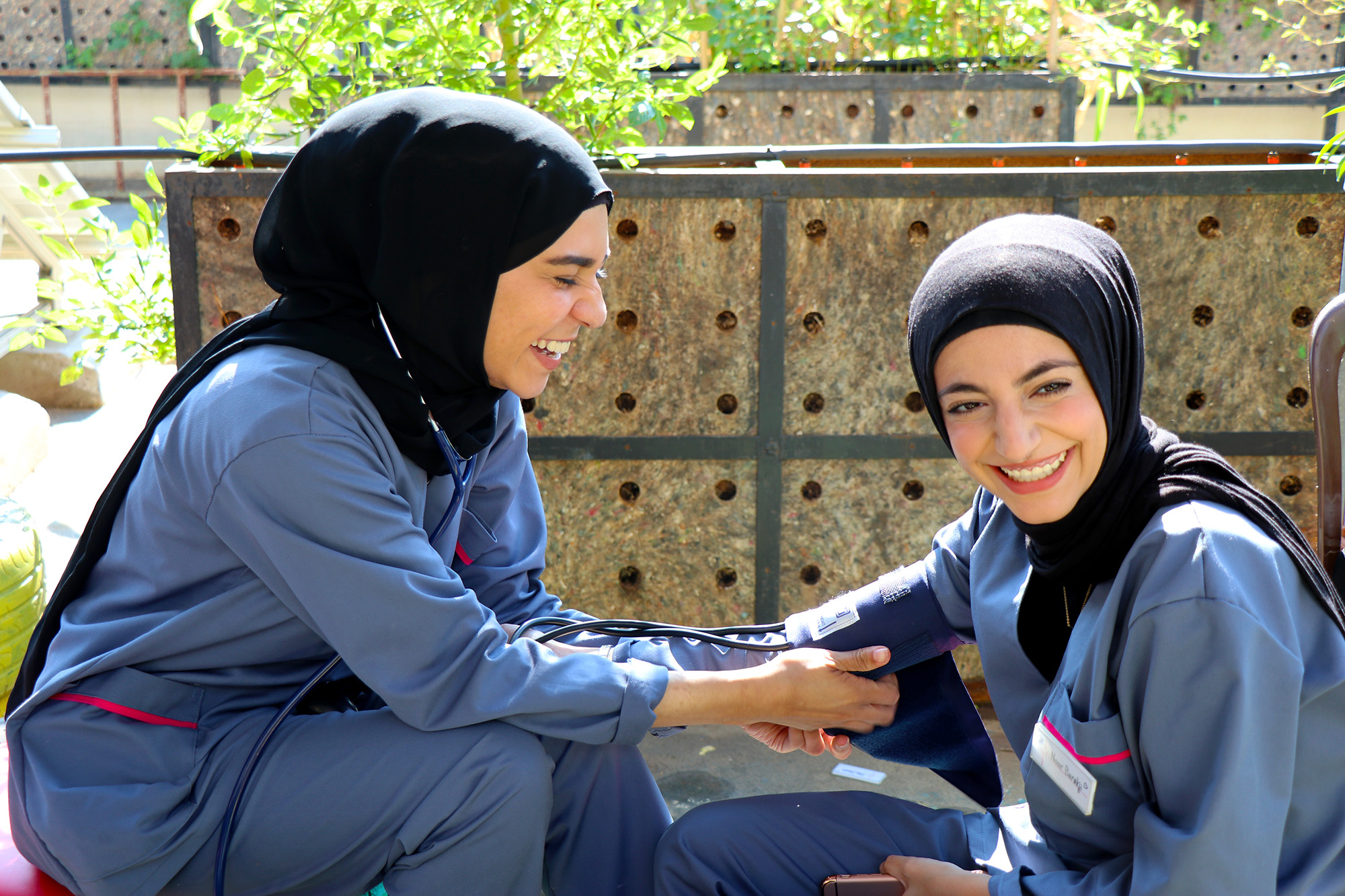 Hiba and Nour practice taking blood pressure readings.