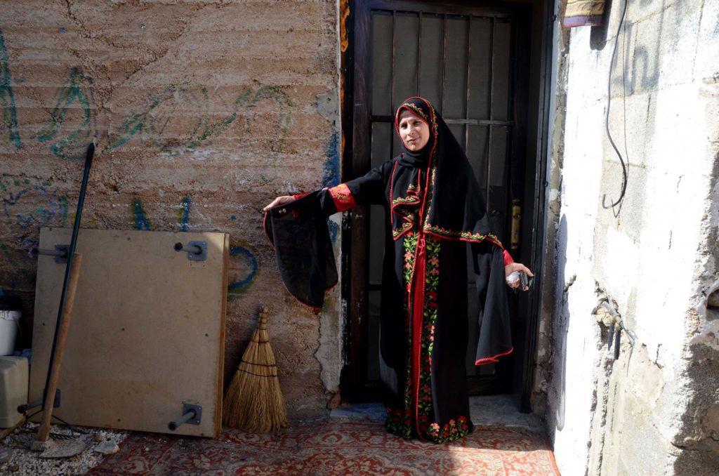 Asmaa, a Palestinian dressmaker, models a dress she made using the sewing machine Anera provided her.