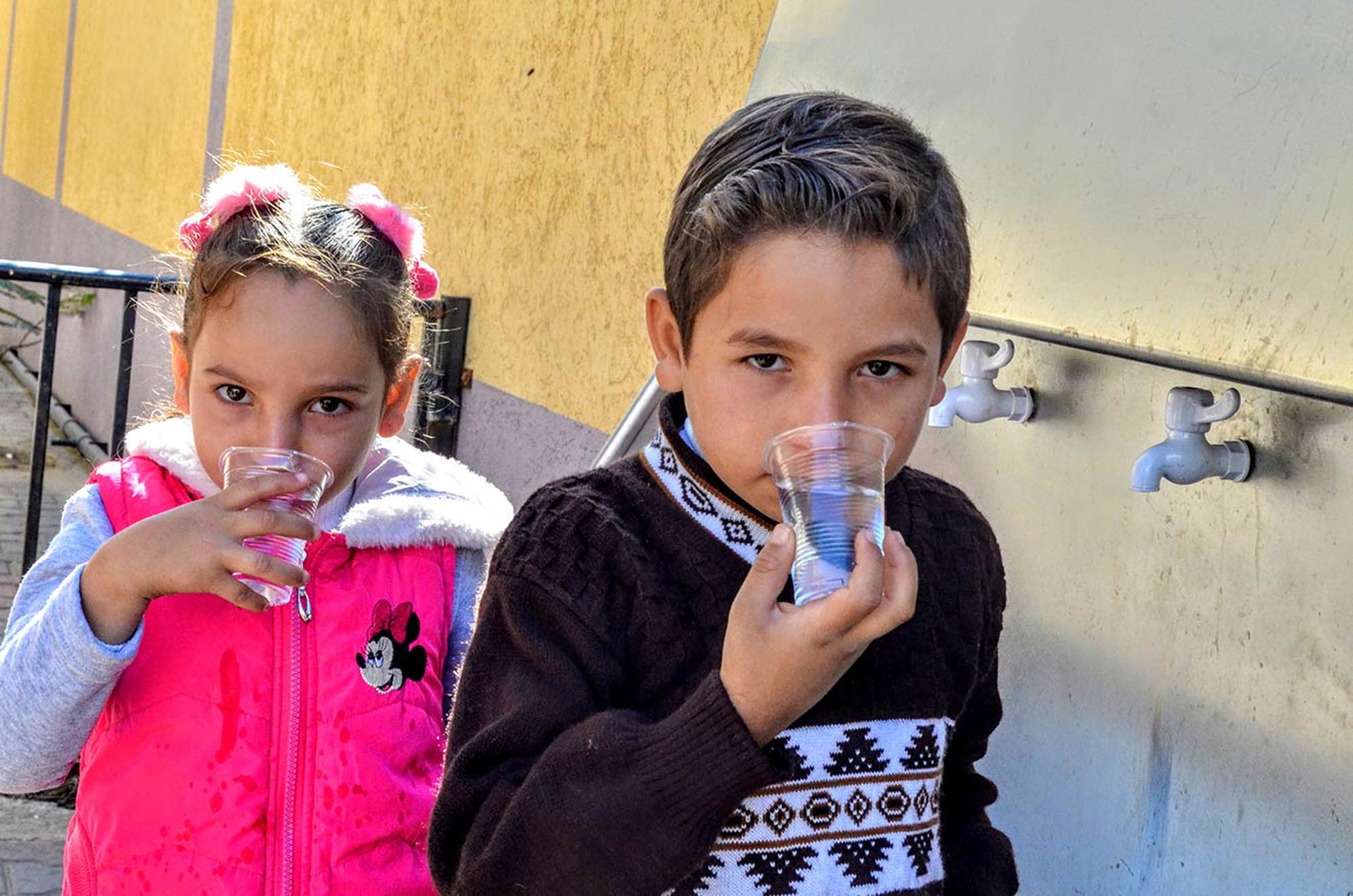 Children drink clean water supplied by a desalination unit at a water fountain at Ard El Insan clinic in Gaza.