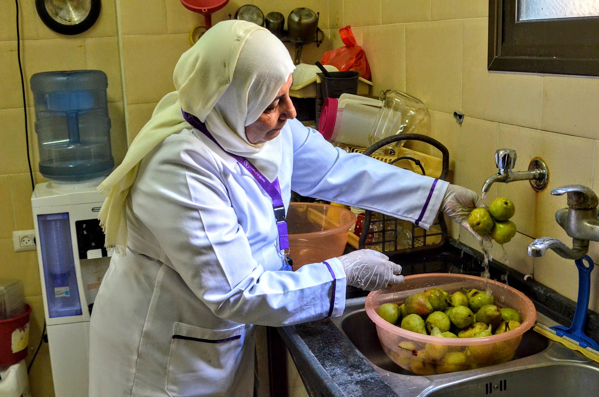 A staff member washes fruit in clean water to prepare a healthy meal for children in Gaza.