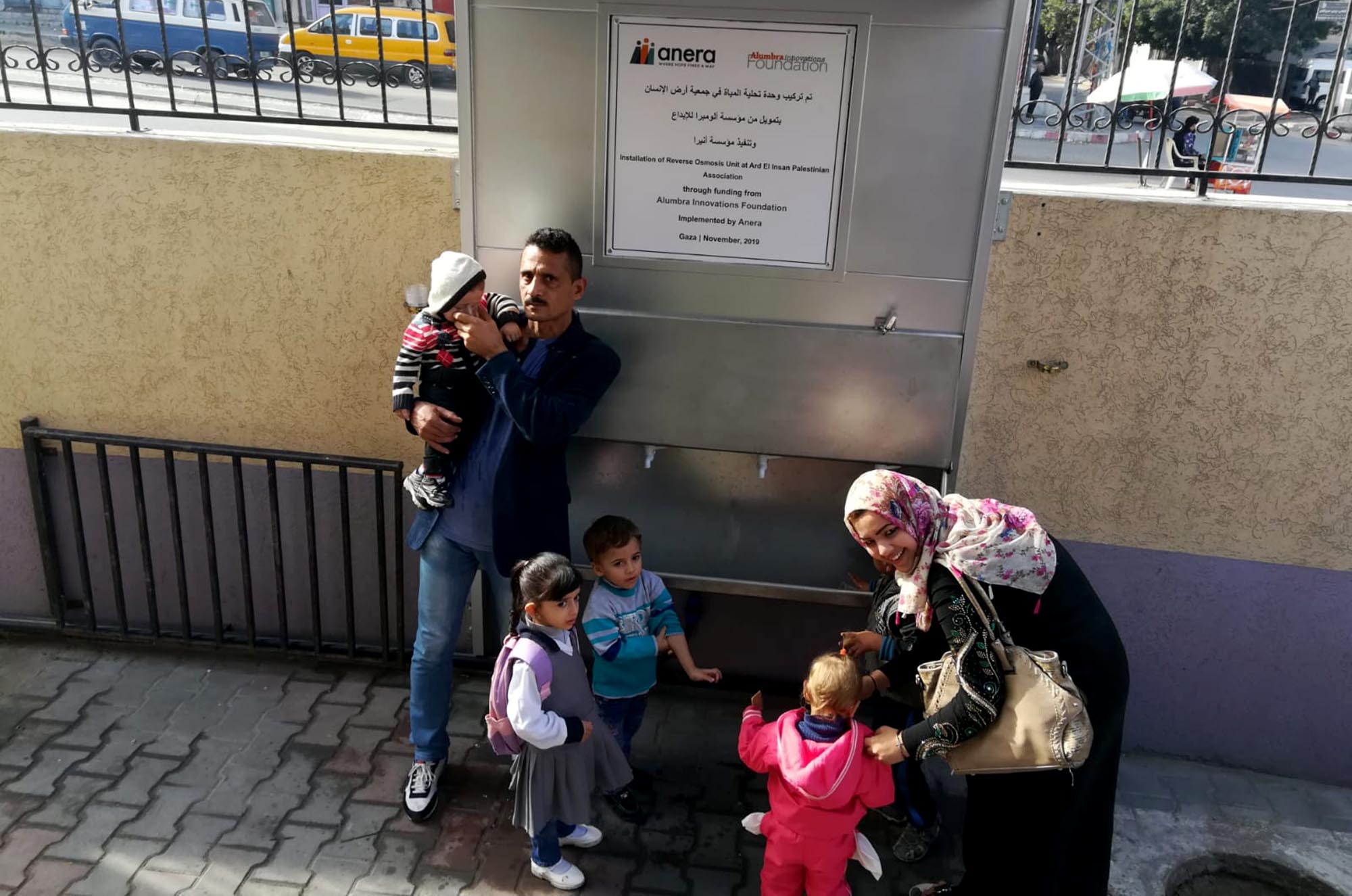A family drinks clean water supplied by a desalination unit at a water fountain at Ard El Insan clinic in Gaza.
