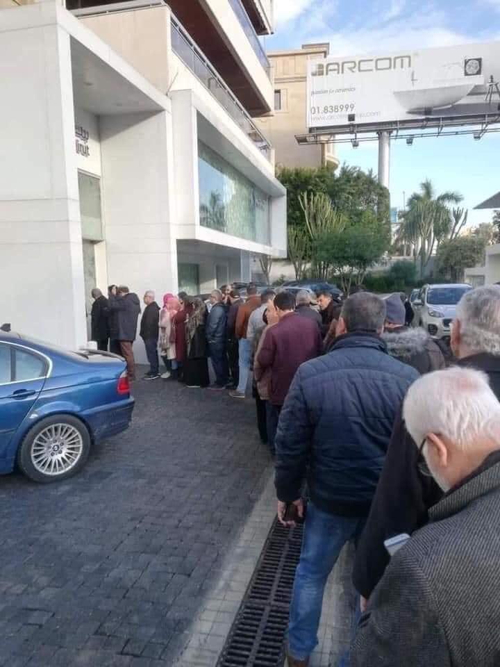 People standing in line outside the Bank of Beirut, waiting to withdraw their weekly allowance.