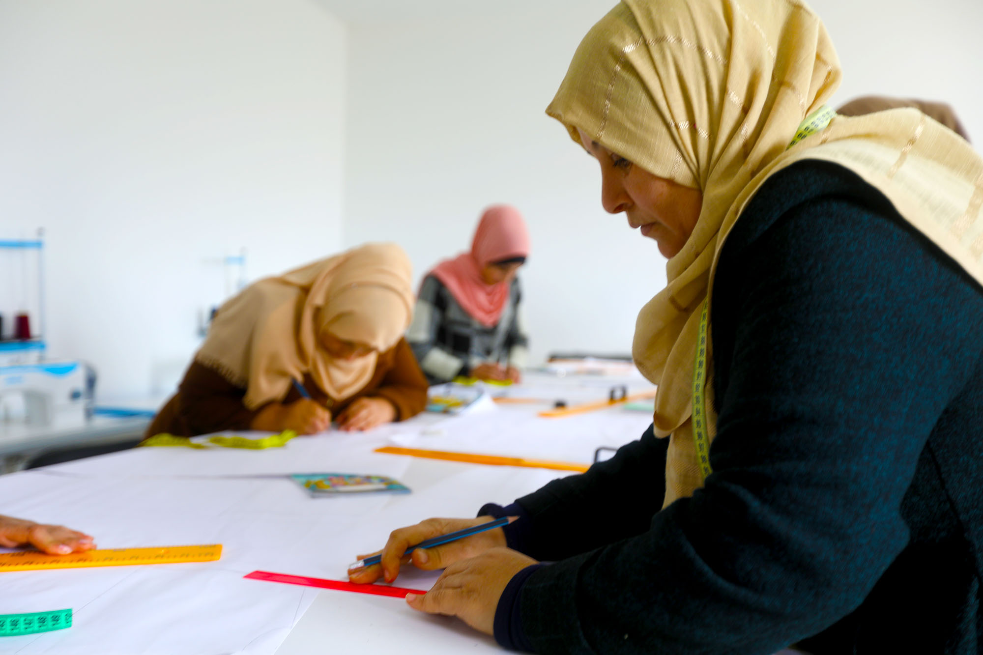 A Palestinian woman measures out the edges of a sewing pattern she is designing as part of a sewing course provided by Anera at the CSSL center in Beit Hanoun, Gaza.