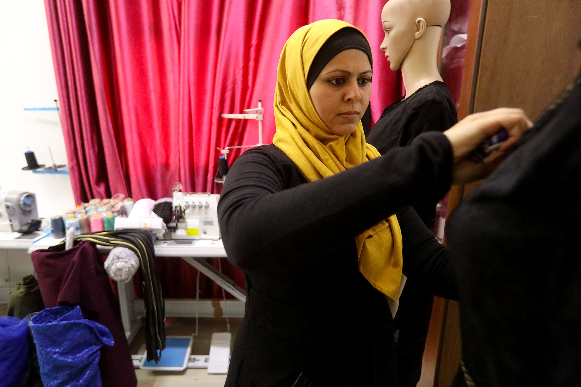 Abeer, the trainer, lays out a design on a mannequin at the CSSL center in Beit Hanoun, Gaza as part of an Anera sewing training course.
