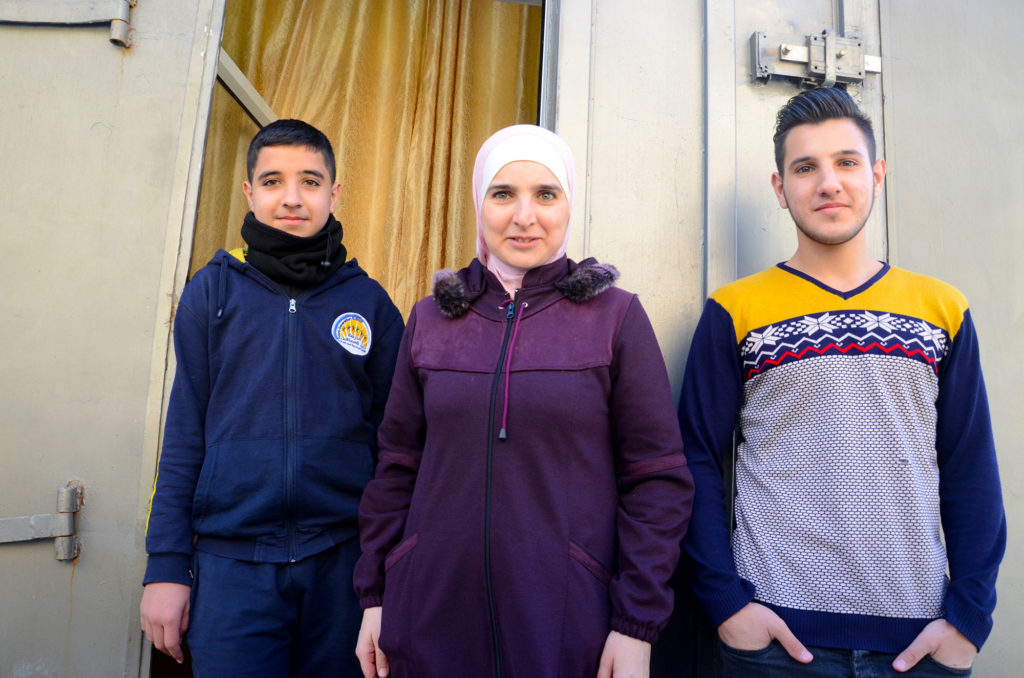 Kholood and her two sons in front of the entrance to her new kitchen.