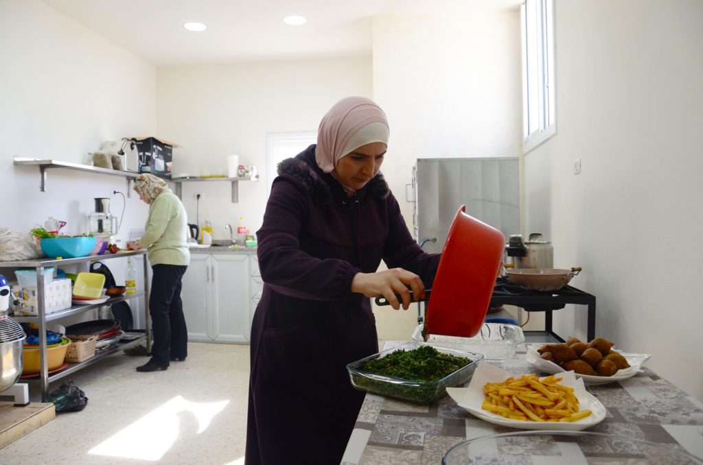 Kholood starts plating her prepared food.