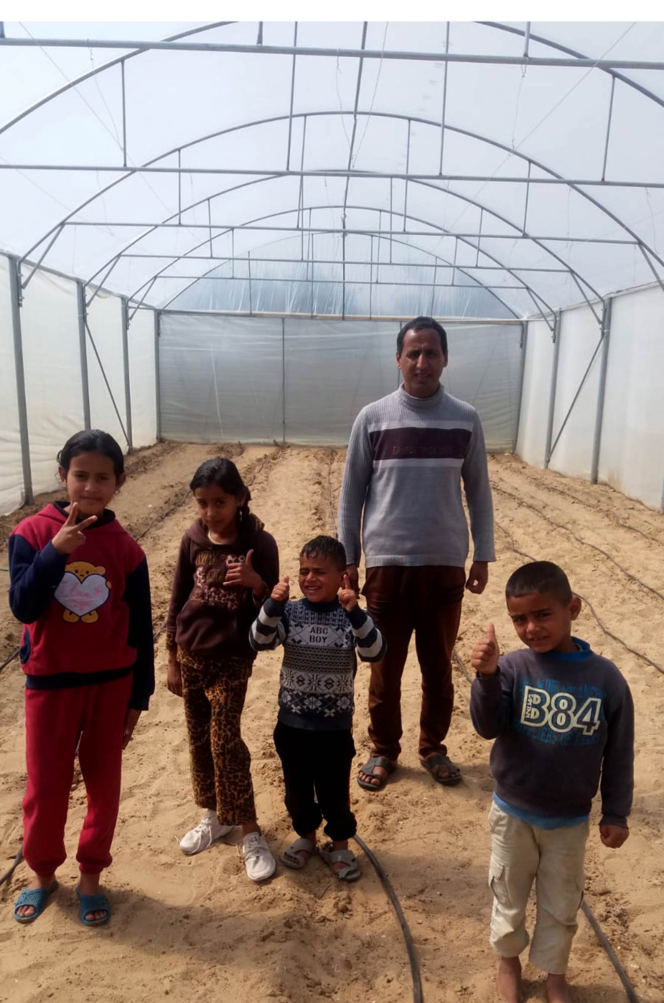 The Abu Sanima family enjoying their new greenhouse in Rafah, Gaza.