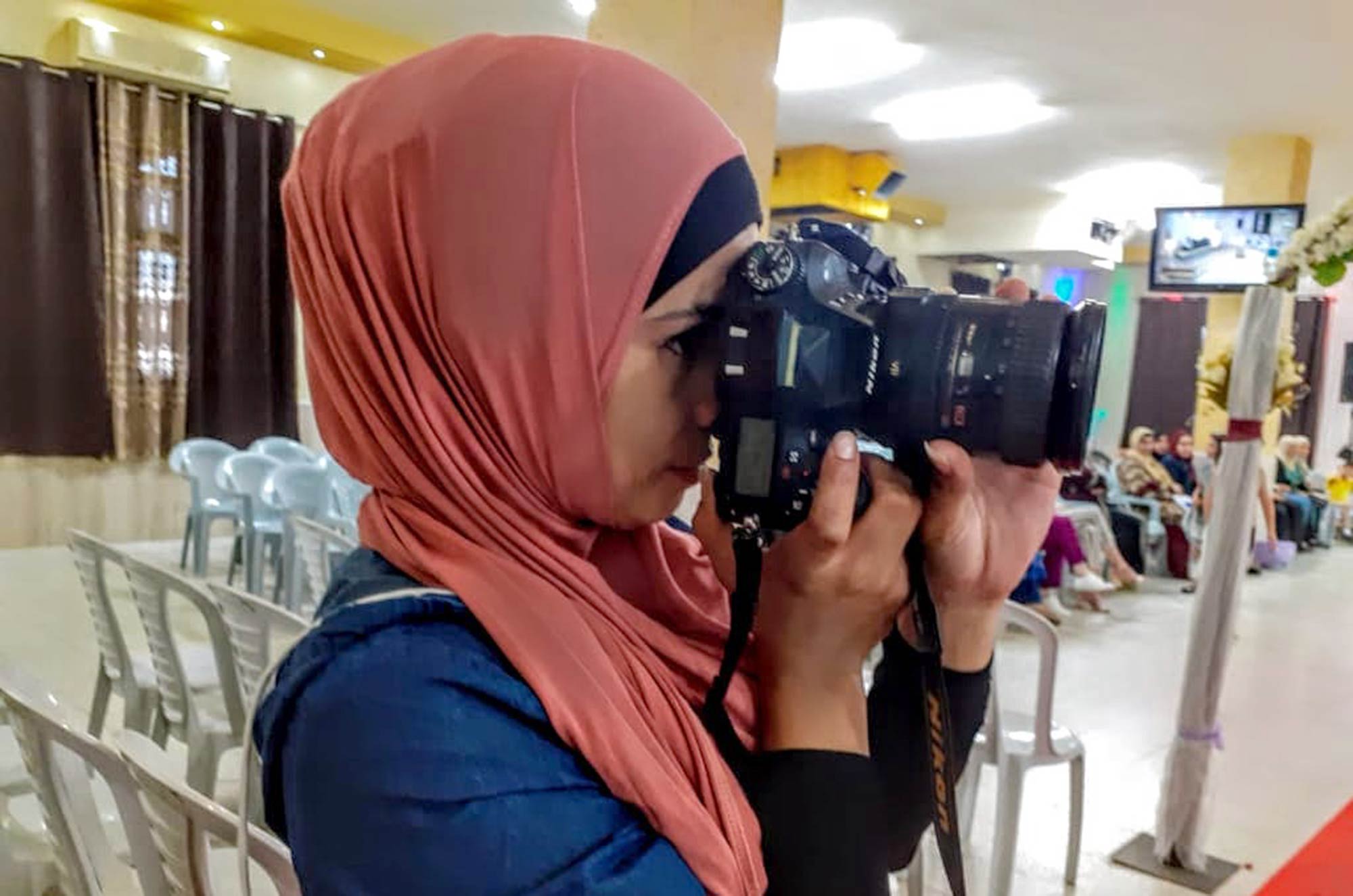 Ahlam, a participant in Anera's Women-Can program, is on the job photographing a wedding.