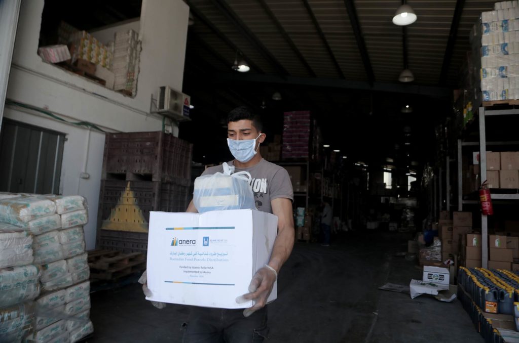 A worker takes a Ramadan food parcel out of the warehouse for distribution