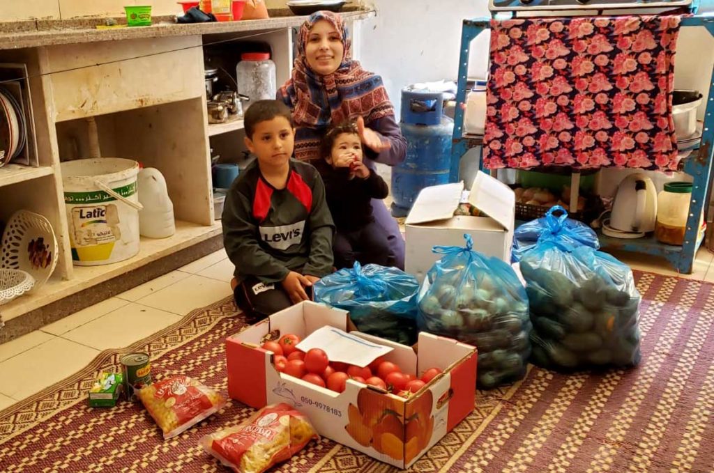 A family in Gaza surrounded by the contents of the Ramadan food parcel they received from Anera.