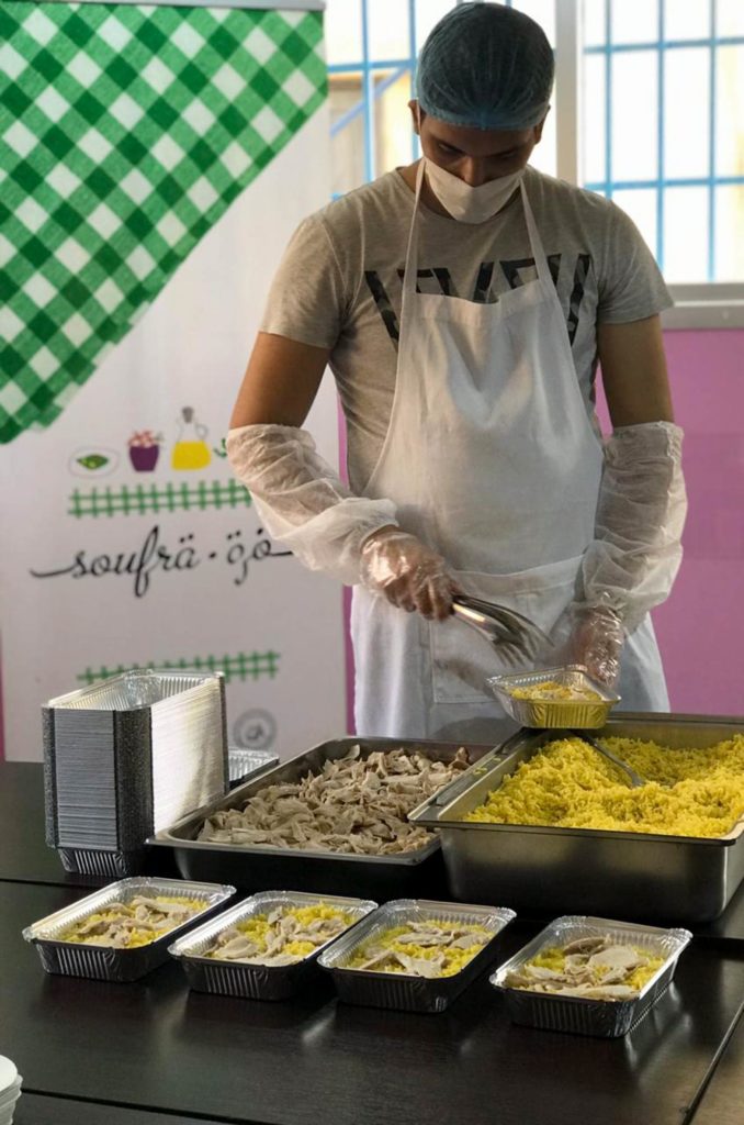 A young man in Soufra's kitchen prepares trays of hot meals.