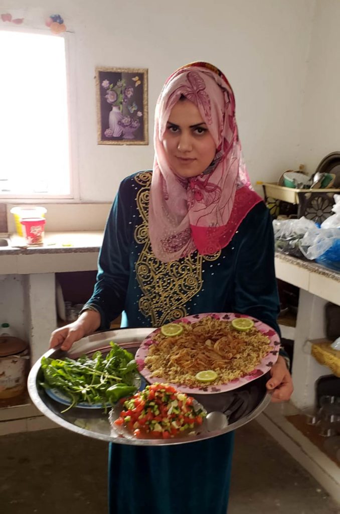 Shireen holds a platter of mujadara and salad