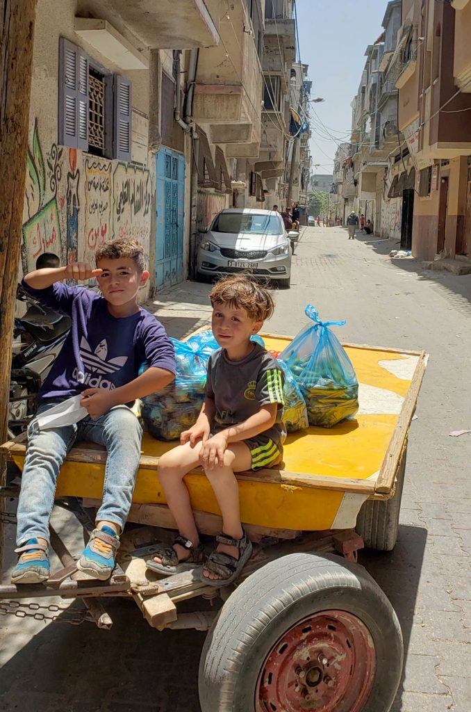Boys in a donkey cart helps collect vegetables from a distribution of vegetables to families in need in Gaza after Ramadan 2020.